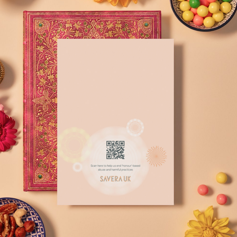 Back of a card with a soft peach background featuring delicate mandala patterns made of circular and starburst geometric shapes in pale yellow and orange. At the bottom center, a glowing white mandala contains a QR code above the text: ‘Scan here to help us end ‘honour’-based abuse and harmful practices.’ Below the text is the orange geometric logo ‘SAVERA UK.