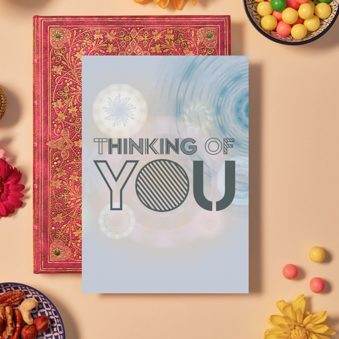 Card with bold dark grey text reading ‘THINKING OF YOU’ in a mix of outlined and striped geometric fonts. The background features soft blue, cream, and peach mandala patterns made of layered circular and floral geometric shapes, creating a calm, reflective, and comforting design.
