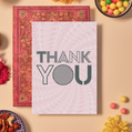 Card with bold dark grey text reading ‘THANK YOU’ in a mix of outlined and striped geometric fonts. The background features a soft pink mandala pattern created from repeating ‘THANK YOU’ text radiating outward in a circular, spiral formation, giving the design a layered and dynamic sense of gratitude.