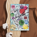 A vibrant, abstract artwork filled with layered textures and bold colours. Circular shapes in red, green, purple, yellow, and blue scatter across the card, with energetic black ink strokes cutting through the background like branches or threads. The textured backdrop is a wash of white and cool blues, giving the impression of movement and depth. The piece radiates emotion, complexity, and energy, an expressive celebration of freedom and creativity.