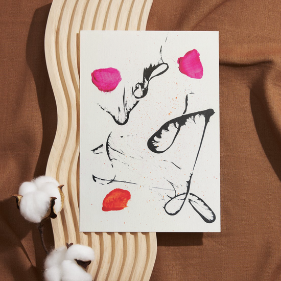 An abstract and expressive illustration printed on textured white card. Bold black ink sketches of butterfly wings and delicate outlines of faces overlap across the page. Three vibrant paint smudges, two hot pink, one deep orange, add contrast and emotion to the piece. Set against a wavy wooden backdrop with warm brown fabric and soft cotton sprigs, the design evokes resilience, beauty, and transformation.